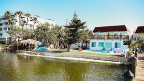 A waterfront hotel with a pool, outdoor seating, and a thatched-roof structure. - Riverfront*Shared Pool*3-Minute Walk to the Beach (202) (Brevard County)