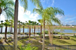 A park with palm trees, a lake, and a pathway.