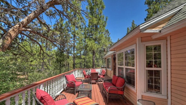 A wooden deck with outdoor furniture, surrounded by trees. - Big Tree Lodge by Destination Big Bear : Ping Pong! Wood Burning Fireplace! Cable! Internet! Propane BBQ! (Big Bear City)