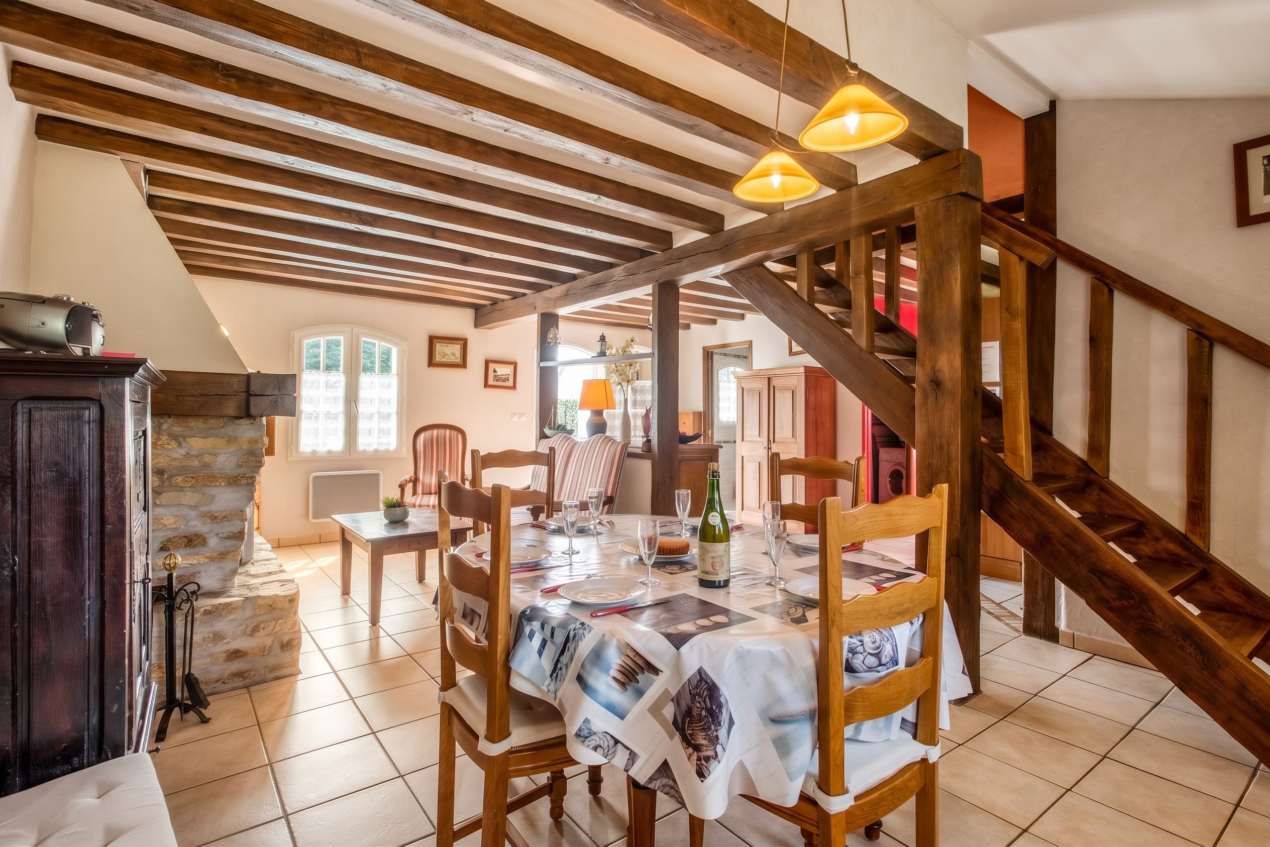 A dining area with a wooden table set for a meal, a staircase, and a stone wall.