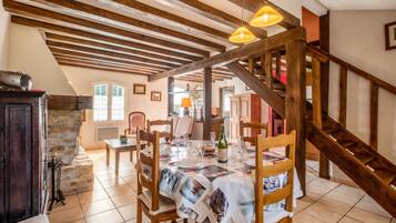 A dining area with a wooden table set for a meal, a staircase, and a stone wall.