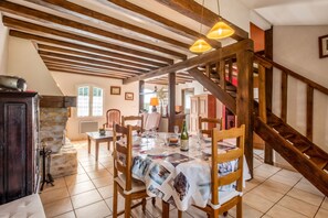 Un comedor con una mesa de madera dispuesta para una comida, una escalera y una pared de piedra.