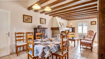 A dining room with a table set for four, wooden chairs, a fireplace, and a television.
