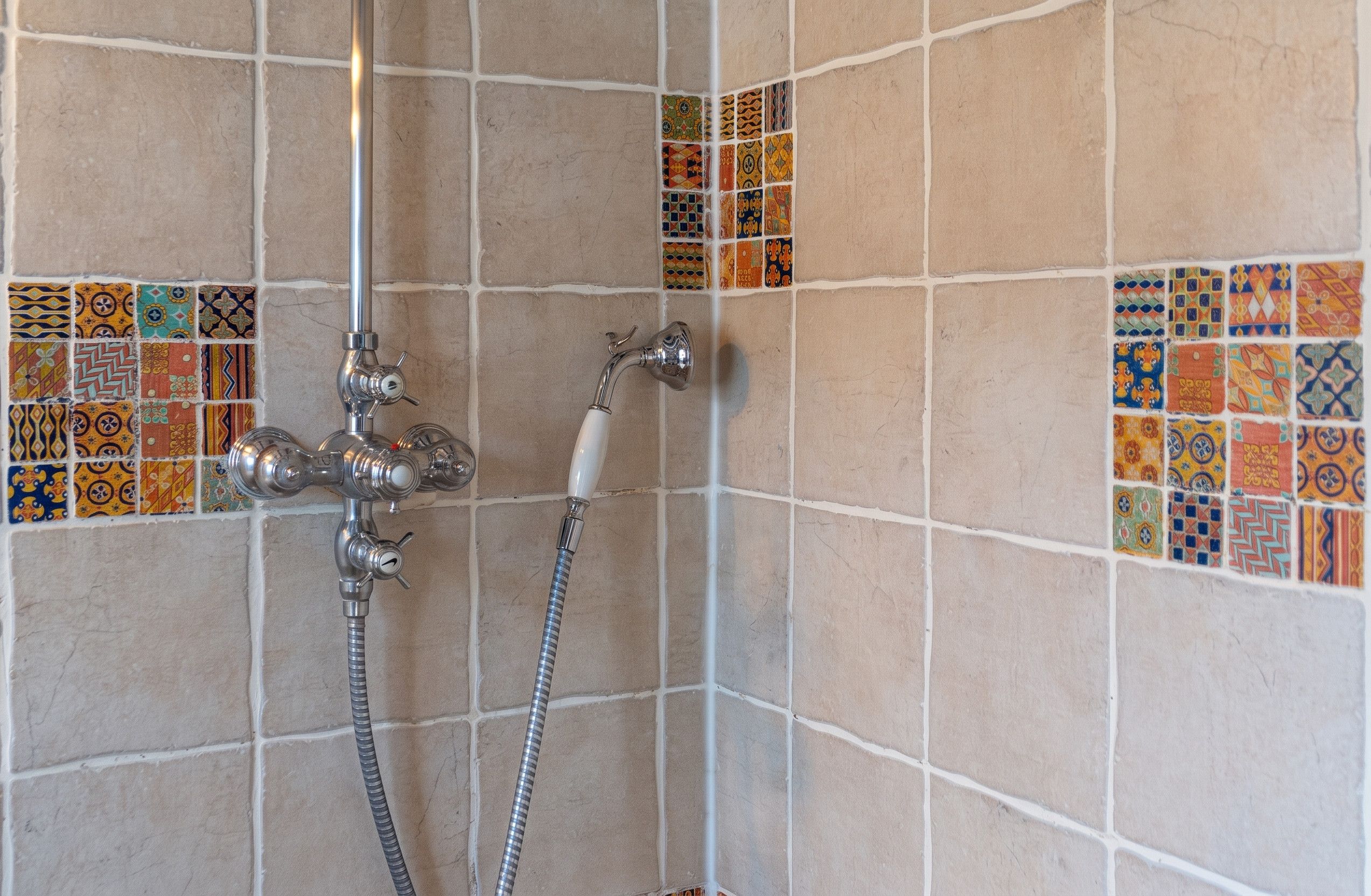 A shower area with a tiled wall and a showerhead.