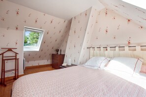 Un dormitorio con cama, cómoda, ventana y una silla de madera.
