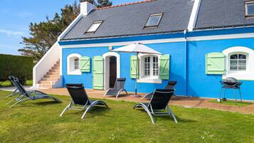 A house with a blue exterior, a grey roof, and a small patio area with outdoor furniture.