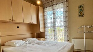 A neatly made bed in a room with a large window, a radiator, and a wall-mounted towel rack. - 2-room apartment, beach access, parking, sleeps 4 - Argelès-sur-Mer (Argelès-sur-Mer)