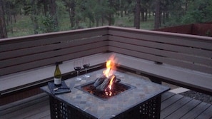 A fire pit table with a bottle and glasses on a deck with a wooden bench. -  A Perfect Vacation Home! Trail Access, Central A/C, Pets Welcome, TOP Reviewed! (Flagstaff)