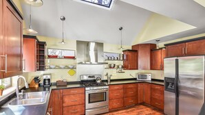 Una cocina con armarios de madera, electrodomésticos de acero inoxidable y un suelo con estampado en patrón de espiga.