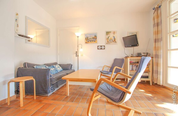 A living room with a sofa, a wooden table, a rocking chair, a TV, and a bookshelf.