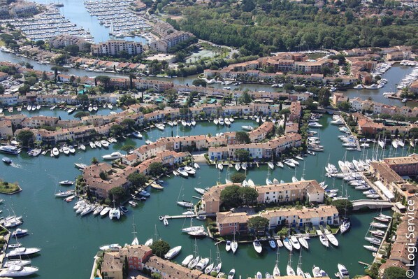 Boats docked in a marina surrounded by Mediterranean-style buildings with terracotta roofs and flat rooftops.