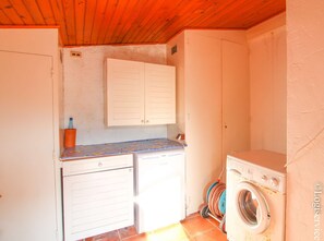 A laundry room with a washing machine, a drying rack, and a cabinet above a countertop.