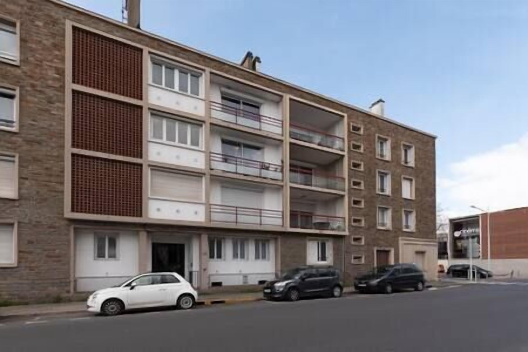 Un immeuble résidentiel à plusieurs étages, doté de balcons et d’un espace de stationnement.