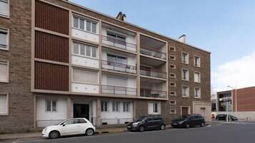 Un immeuble résidentiel à plusieurs étages, doté de balcons et d’un espace de stationnement.