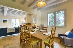 A dining area with a wooden table set for four, surrounded by chairs with cushions.