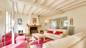 A living room with a fireplace, red and white furniture, and a large mirror. - Hossegor Lake, 10 pers Villa (SEIGNOSSE)