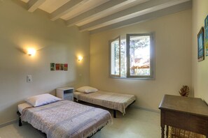 A bedroom with two single beds, a small bedside table, a window, and wall-mounted lights.