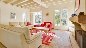 A spacious living room with a high ceiling, a fireplace, and large windows. - Hossegor Lake, 10 pers Villa (SEIGNOSSE)