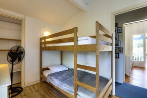 A bunk bed with a fan and a door leading to another room.