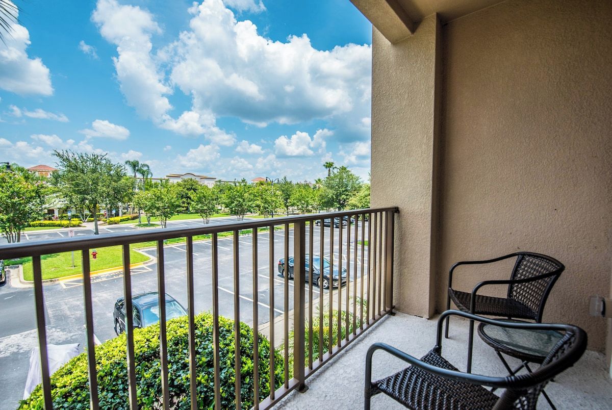 A balcony with a view of a parking lot and buildings.