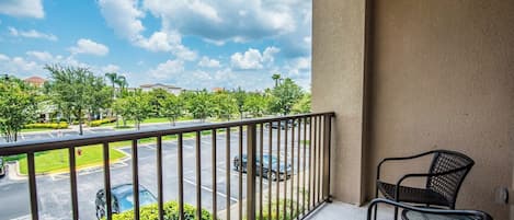 A balcony with a view of a parking lot and buildings.