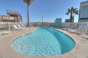A clear blue pool with white lounge chairs and a fenced deck area.