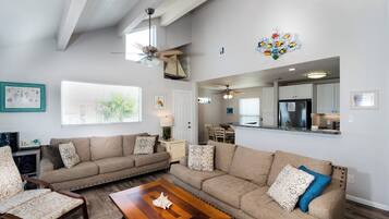 A spacious living room with a large sectional sofa, a wooden coffee table, and a ceiling fan.
