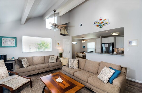A spacious living room with a large sectional sofa, a wooden coffee table, and a ceiling fan.