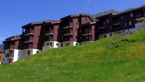 Un hotel de varios pisos con balcones, con montañas al fondo.