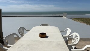 A concrete patio with a table and chairs, a view of the beach, and a metal fence. - Seaside apartment with terrace and parking (Jullouville)
