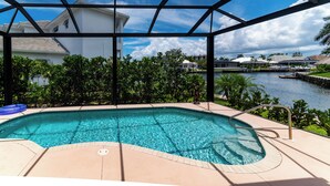 A swimming pool with a view of a canal and houses in the background.