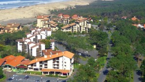 A coastal resort with multiple-story buildings, a parking area, and a beach in the background. - Cozy Studio Near Ocean, Shops & Market in Seignosse (Seignosse)