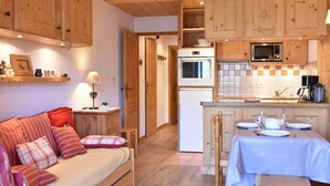 A cozy cabin interior with a sofa, dining table, and kitchenette.