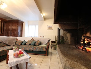A cozy living room with a sofa, a table with candles, and a fireplace.