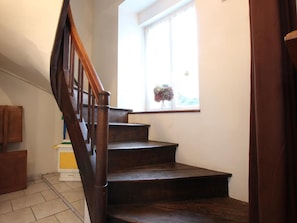 A wooden staircase leading to a landing with a window above.