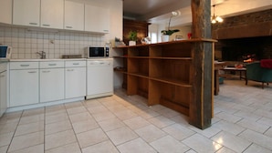Une cuisine moderne avec des armoires blanches, un four à micro-ondes et une étagère en bois.