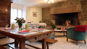 Un salon chaleureux avec une cheminée en pierre, des meubles en bois et un coin repas aménagé pour prendre un repas.