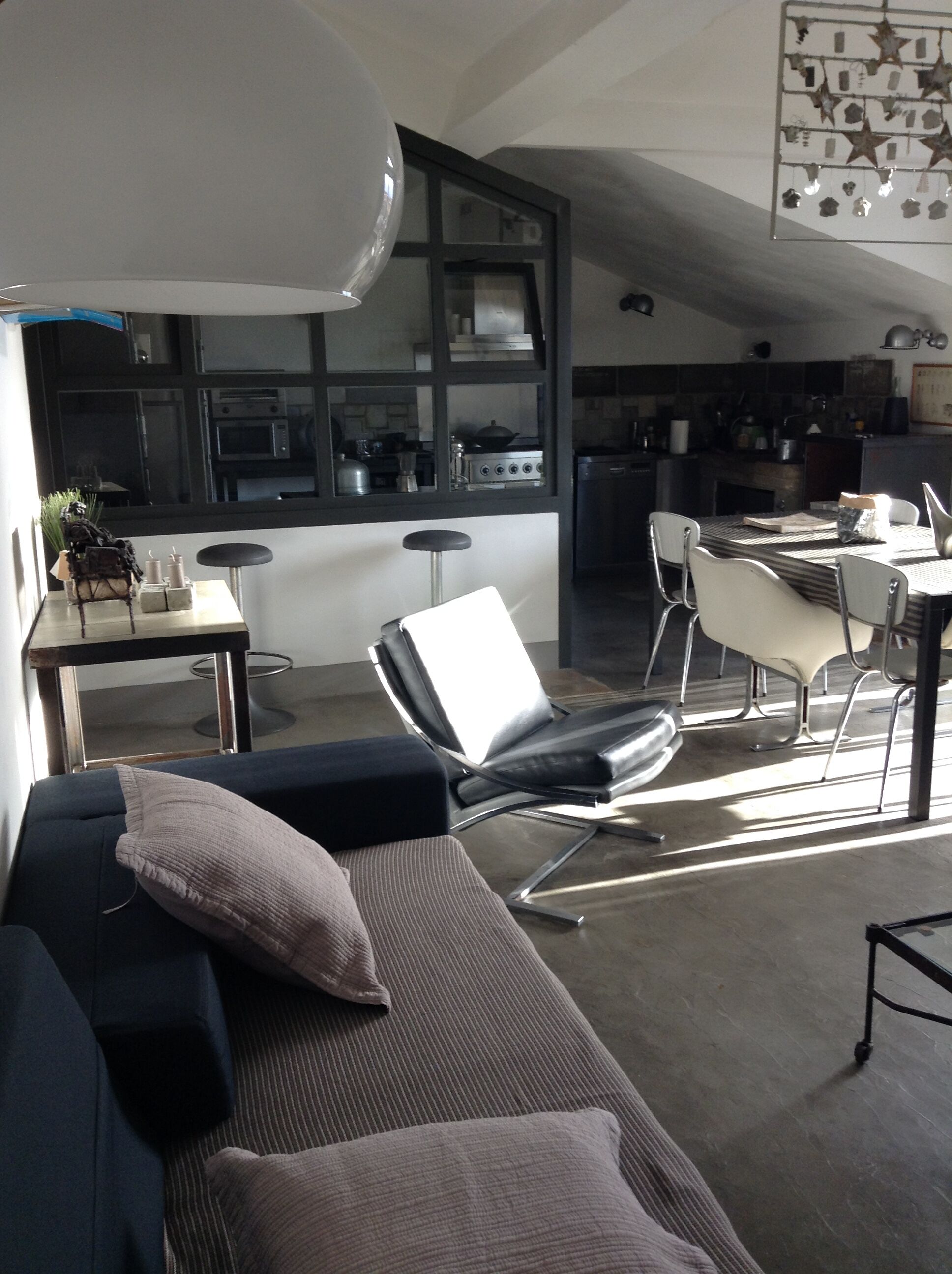 Ein modernes Wohnzimmer mit einer Couch, einem Essbereich mit Tisch und Stühlen sowie einer Küche im Hintergrund.