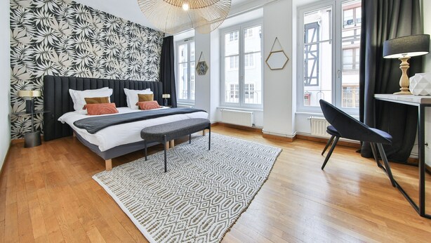 A modern bedroom with a bed, bedside tables, a desk, and a chair. - Tussaud spa 75m2 city center up to 4 (Colmar)