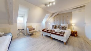 Ein modernes Schlafzimmer mit einem großen Bett, einem Sessel, einem Heizkörper und einem Fenster.