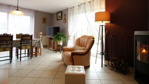 A living room with a fireplace, a dining area with a table and chairs, a sofa, and a lamp.