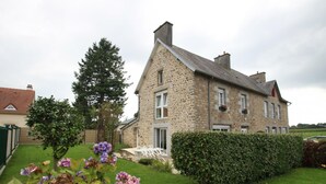 A stone house with a well-maintained lawn and a hedge.