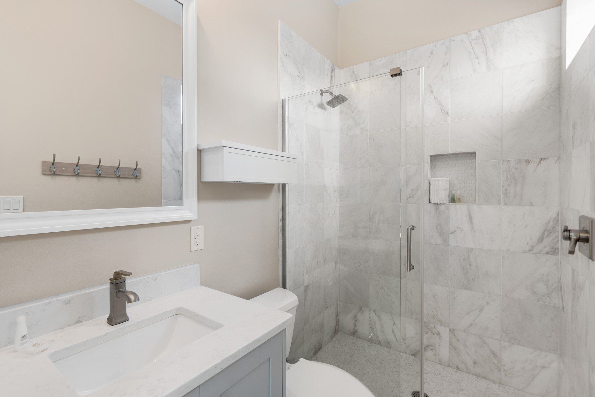 Un baño moderno con ducha de mármol, lavabo y espejo.
