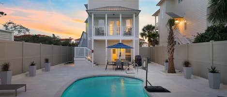 A two-story house with a swimming pool, outdoor seating, and a staircase leading to the upper floor.