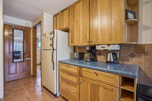 Compact kitchen area with refrigerator, coffee maker, and toaster, plus a convenient shelf for storage.