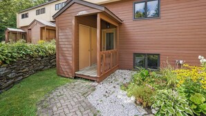 A modern building with a wooden exterior, a covered porch, and a stone wall.