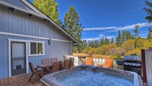 A hot tub on a wooden deck with a view of a forested area.