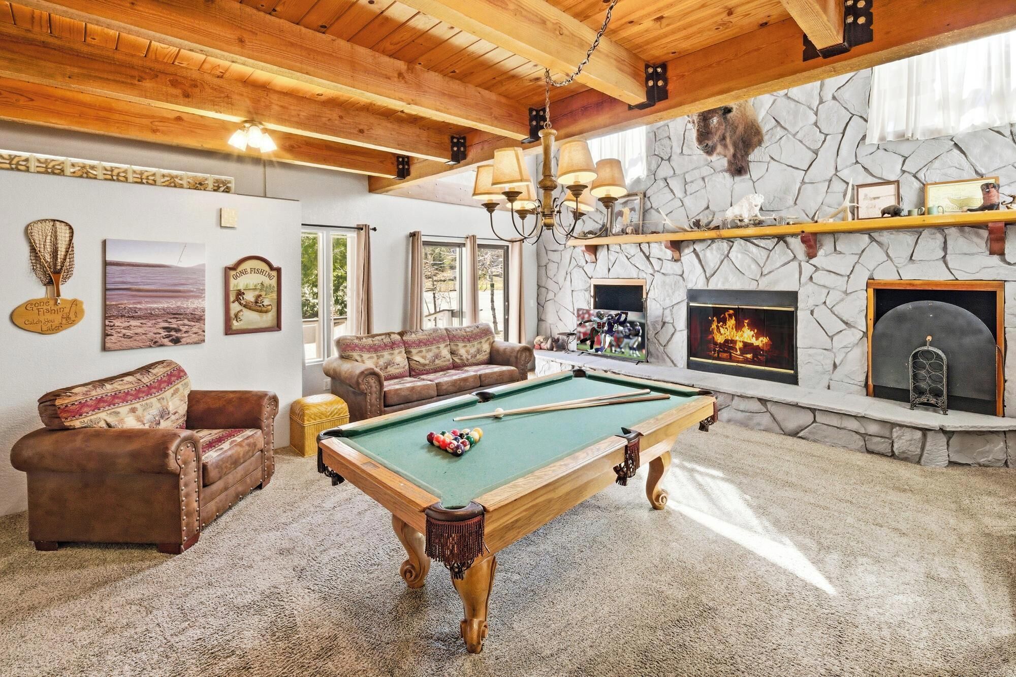 Ein gemütliches Wohnzimmer mit Billardtisch, Kamin aus Stein und einer bequemen Sitzecke.