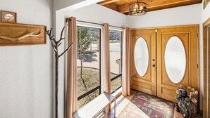 A wooden door with frosted glass panels, a bench, a rug, and a wall-mounted sign.