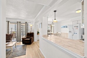 A modern living room with a sofa, a coffee table, and a dining area with chairs and a table.